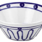 A white ceramic bowl from Themis Z’s Kyma Blue Dinnerware Collection features blue geometric patterns, inspired by the Greek Aegean Sea.