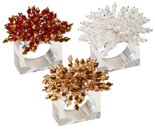 Three Kim Seybert Brilliant Napkin Rings by Kim Seybert, featuring hand-crafted, square designs with intricate beaded floral patterns in red, white, and brown colors, are displayed against a white background. Their unique crystal-like accents add an elegant touch to any table setting.