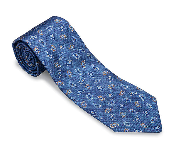 The R. Hanauer Brinkley Pine Necktie by R. Hanauer is a rolled-up silk necktie featuring an orange and white paisley pattern against a light grey background, measuring 57" long and made in the USA.