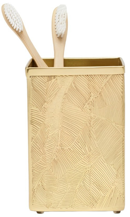 A gold-colored, textured toothbrush holder from Pigeon & Poodle's Mancora Bath Collection features a shiny finish and holds two bamboo toothbrushes with white bristles.