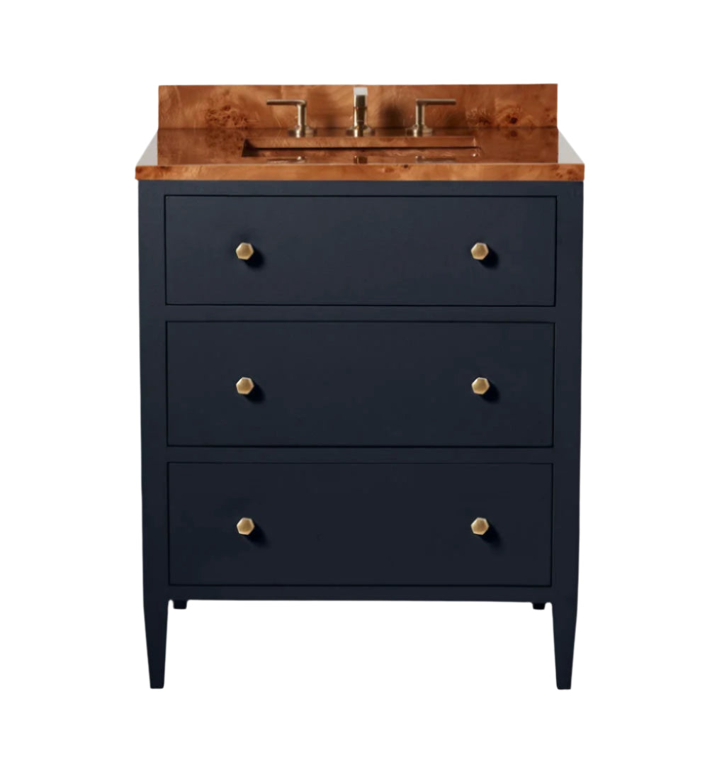 The Jarin Vanity Collection by Made Goods features a dark blue freestanding base, three drawers with gold knobs, and a wood countertop with an integrated sink and faucet.