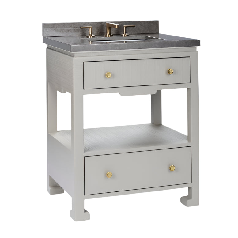 The Wylder Vanity Collection by Made Goods features a gray faux raffia bathroom vanity with a stone countertop, brass faucet, soft-close drawers, and an open shelf.