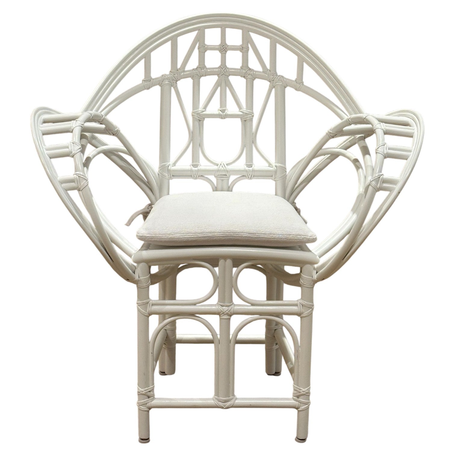 The Butterfly Chair by McGuire Furniture features white rattan with an intricate geometric backrest, armrests, and a light seat cushion—a design inspired by Edward Tuttle’s refined aesthetic.