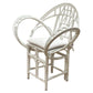 The Butterfly Chair by McGuire Furniture features white rattan, curved armrests, a rounded backrest, and a cushioned seat, inspired by Edward Tuttle for stylish comfort.