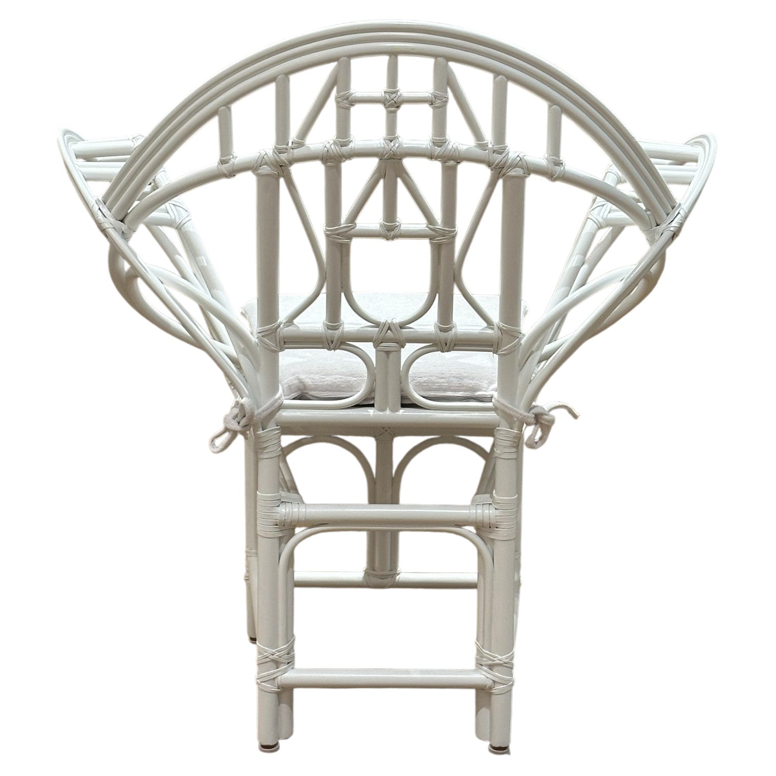 The Butterfly Chair by McGuire Furniture features a white rattan frame with an intricate, geometric backrest inspired by Edward Tuttle and a tied-on seat cushion, shown from the back.