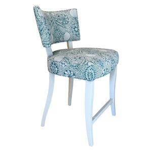 The A. Rudin Counter Stool in Turquoise Shell Grato features a white wooden frame with cushioned seat and back, upholstered in teal and white seashell-patterned fabric—ideal for contemporary stylish spaces.