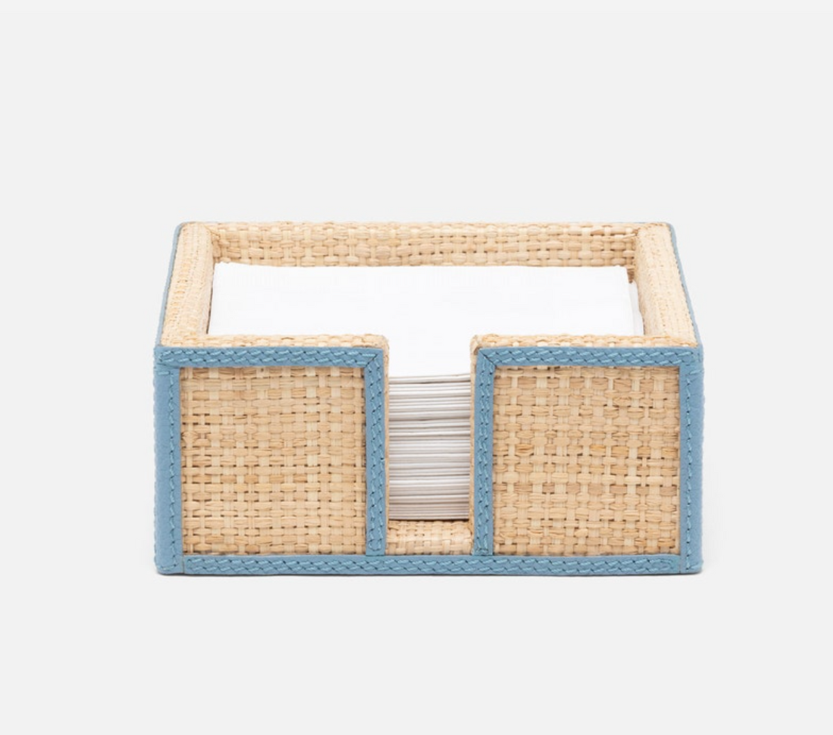 The Gable Natural/White Barware Collection by Blue Pheasant features a woven rectangular napkin holder with leather trim and white napkins against a plain background.