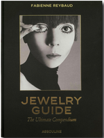 Cover of the book "Jewelry Guide: The Ultimate Compendium" by Assouline, featuring a black and white photo of a person holding a piece of jewelry and showcasing its intricate gems up to one eye.