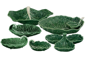 The HIVE Cabbage Leaf Green Collection is a ceramic handmade serveware set from Portugal, featuring leaf-shaped dishes, bowls, a serving spoon, and a divided dish.