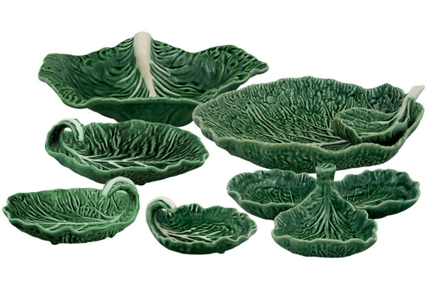 The Bordallo Pinheiro Cabbage Leaf Green Collection, featuring handmade ceramic serving dishes shaped like cabbage leaves, is arranged in various sizes on a white background.