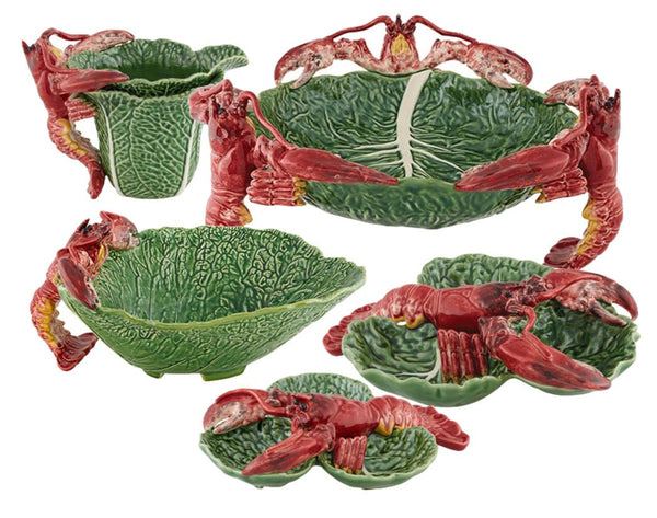 The Bordallo Pinheiro Cabbage with Lobsters Serveware Collection features cabbage-shaped ceramic dishes, including bowls and platters, adorned with vibrant red lobster motifs.