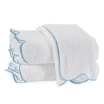 Three white luxury towels from the Matouk Cairo Scallop Bath Collection, featuring light blue trim and crafted from premium long-staple cotton, are neatly stacked with one draped over the top.