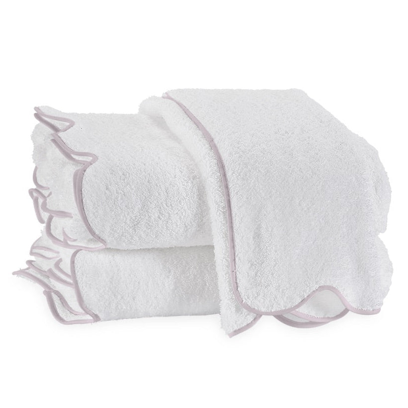 These two folded white terry towels from the Matouk Cairo Scallop Bath Collection feature scalloped edges with pink borders, crafted from luxurious long-staple cotton for ultimate softness.
