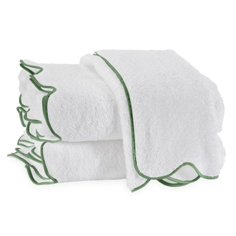 A neatly folded stack of white terry towels with green edges highlights the exquisite Matouk Cairo Scallop Bath Collection, crafted from long-staple cotton.