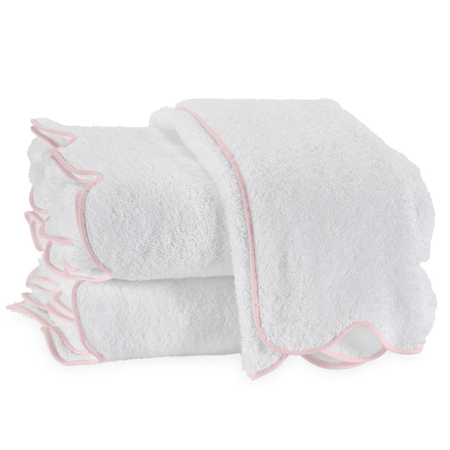 Three terry towels from the Matouk Cairo Scallop Bath Collection, with pink-trimmed edges, are neatly folded and arranged against a pristine white background.