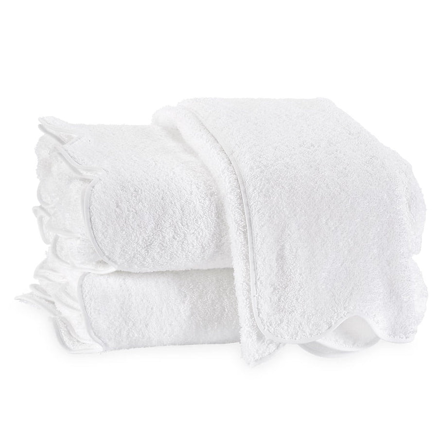 Two neatly folded white terry towels from the Matouk Cairo Scallop Bath Collection, crafted with premium long-staple cotton, stacked atop one another against a plain white background.