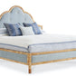 The Sloane King Bed by Mr & Mrs Howard features a tall, curved light blue upholstered headboard with button accents, a sturdy wooden frame, and comes styled with blue and white pillows and bedding.