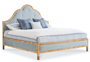 The Sloane King Bed by Mr & Mrs Howard features a tall, curved light blue upholstered headboard with button accents, a sturdy wooden frame, and comes styled with blue and white pillows and bedding.