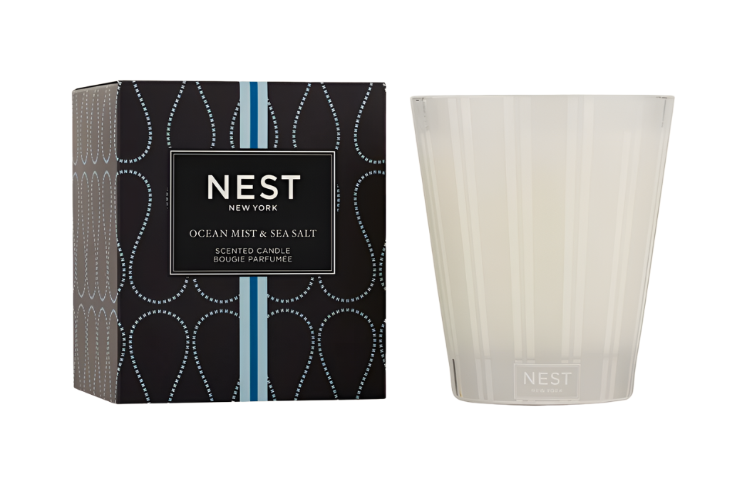 A Nest Ocean Mist & Sea Salt Candle from the Candle Collection sits by its stylish black and blue box, filling the room with refreshing ocean mist and sea salt fragrance.