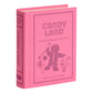 A pink, fabric-wrapped book-shaped box from WS Game Company’s Vintage Bookshelf Board Games, featuring Candy Land-themed artwork with a gingerbread figure and candy canes on the cover.