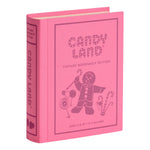 A pink, fabric-wrapped book-shaped box from WS Game Company’s Vintage Bookshelf Board Games, featuring Candy Land-themed artwork with a gingerbread figure and candy canes on the cover.