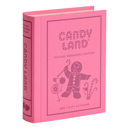 A pink, fabric-wrapped book-shaped box from WS Game Company’s Vintage Bookshelf Board Games, featuring Candy Land-themed artwork with a gingerbread figure and candy canes on the cover.