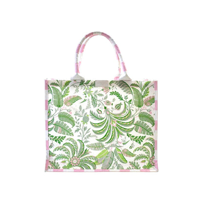 The Addison Ross Palm Beach Tote Bag features pink and green botanical prints, two top handles, and a pink-striped trim on cotton canvas, shown against a white background.