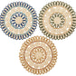 Three round, handwoven coasters by Kim Seybert feature intricate looped patterns in green corn husk, outlined in blue, green, and tan—artfully arranged to reflect the Casbah Placemat’s artisanal style.
