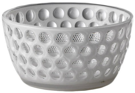 The Lente Acrylic Dinnerware Collection by Mario Luca Giusti features clear glass-look bowls with raised round bumps, ideal for outdoor entertaining or pairing with blue pieces for a vibrant table setting.