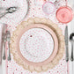 The Heart Placemat Collection by Juliska, featuring hand-woven abaca mats with pink and white heart details, pairs beautifully with elegant pink glassware and silver utensils to create charming tablescapes for any celebration.