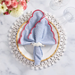 A table setting featuring the Kim Seybert Fiesta Napkin Set, a white plate, beaded placemat, white napkin ring, clear glasses, and a floral arrangement.