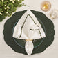 A festive table setting featuring a green charger, white plate, and an embroidered napkin elegantly secured with a Kim Seybert Chain Link Napkin Ring, accompanied by two glasses and lush greenery on a light wooden table.