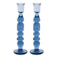 The Provence Candlestick Set by Juliska features two tall, blue mouth-blown glass holders with rounded, stacked shapes and wide bases—a striking pair for lovers of vibrant glassware.