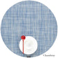 A red spoon rests on a white cup and saucer atop the Chilewich round blue placemat from the Chambray collection, crafted from phthalate-free Terrastrand yarns.
