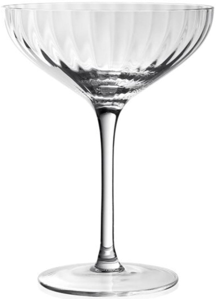 The Corinne Collection coupe by William Yeoward Crystal features clear glass with a wide, shallow bowl, elegant vertical optic pattern, long stem, and flat base—an Art Deco-inspired design set against a plain white background.