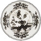 The Oriente Italiano Albus Dinnerware Collection by Ginori 1735 features porcelain plates with scalloped edges and intricate black floral and geometric designs on a white background, inspired by timeless elegance.