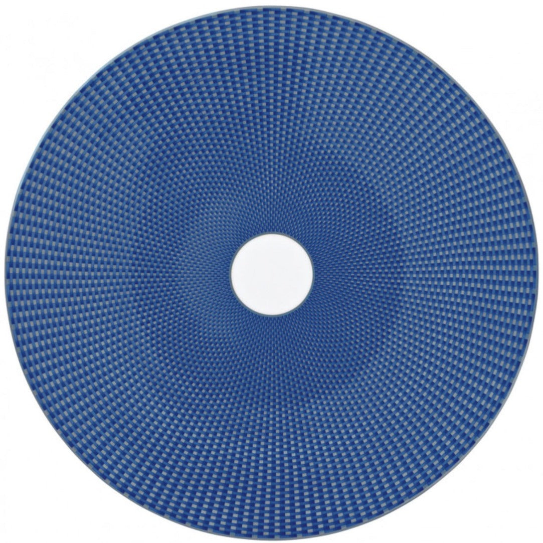 The Tresor Blue Dinnerware Collection by Raynaud features a round blue porcelain plate with a woven geometric pattern and a white center, offering subtle elegance.
