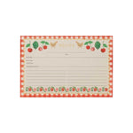 The Cherries Collection recipe card by Rifle Paper Co. features a red checkered border, cherry motifs, fruit and chicken illustrations, and labeled sections for notes, prep time, total time, and ingredients.