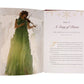 An open book from Anne Neilson's "Christmas Angels: Devotions and Art of Hope and Joy for the Advent Season" shows a woman in a green dress playing violin on one page, and text titled "Day 17: A Song of Praise" on the other.
