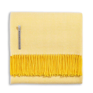 Alicia Adams Alpaca Classic Herringbone Throw: a folded yellow baby alpaca blanket with darker yellow fringe, fair-trade made in Peru, features a herringbone pattern and side fabric tag.