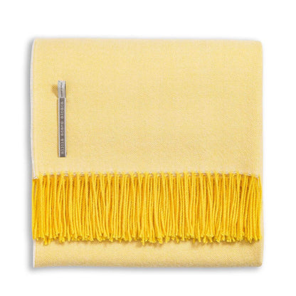 Alicia Adams Alpaca Classic Herringbone Throw: a folded yellow baby alpaca blanket with darker yellow fringe, fair-trade made in Peru, features a herringbone pattern and side fabric tag.