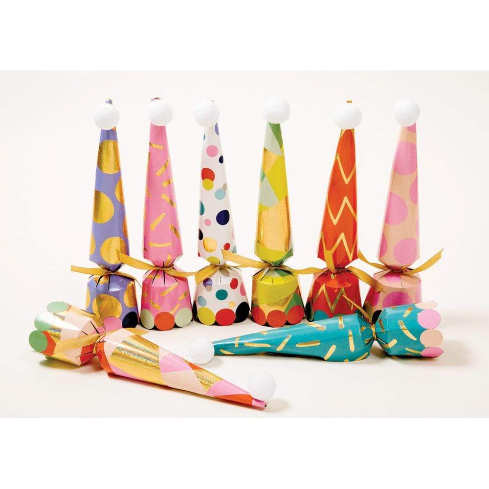 Eight Caspari Party Hat Crackers with vibrant patterns and gold bows stand upright, while three lie in front on a white surface—festive accessories to brighten any celebration.