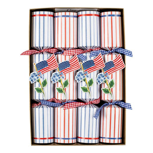 The Caspari Flags And Hydrangeas Collection features party crackers decorated with small American flags and blue hydrangeas, tied with checkered ribbons—perfect for adding patriotic flair to festive picnics or outdoor gatherings.