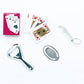 The Caspari Cheers To You Crackers set includes playing cards, a silver bottle opener, a keychain corkscrew, and a round metal trinket, all arranged on a white surface.