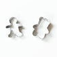Two metal cookie cutters, inspired by classic Caspari designs and featured with White Christmas Crackers, are placed on a white background—one upright, one tilted.