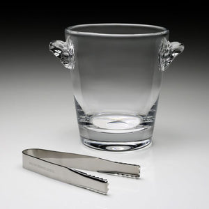 The William Yeoward Crystal Classic Ice Bucket, handmade with two handles, sits behind a pair of metal ice tongs on a neutral surface.