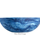 A large blue bowl with a marbled wave pattern from the Denim Resin Serveware Collection by Nashi Home rests on a white background. Crafted from shatter-resistant resin, it adds unique style to your home. Text: "Wave Bowl Large.