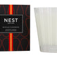 A Nest Sicilian Tangerine Candle from the Sicilian Tangerine Candle Collection sits in a clear glass holder beside its signature black and orange box, crafted with premium wax for a luxurious fragrance experience.