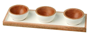 The Be Home Madras Classic Dipping Bowl Set features three small handcrafted mango wood bowls with white exteriors, elegantly arranged on a rectangular wooden tray for a sustainably sourced presentation.