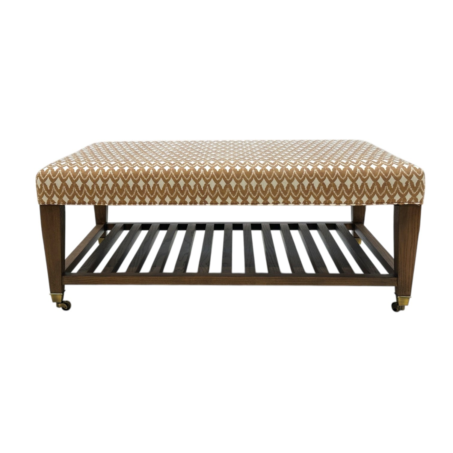 The Lee Industries Upholstered Cocktail Ottoman features an arrowhead patterned fabric, wooden legs with small wheels, and a lower slatted shelf.